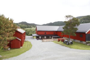 Gårdsbygninger i rødt med tun og gamle traktorer