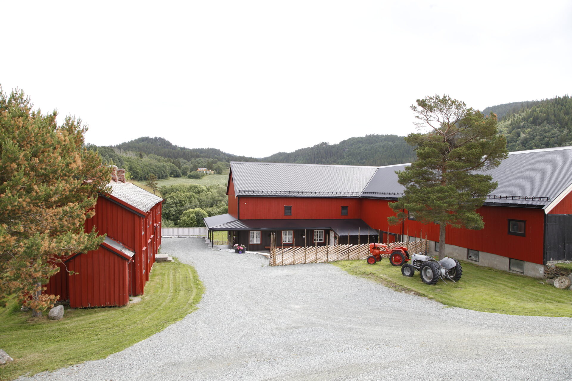 Gårdsbygninger i rødt med tun og gamle traktorer