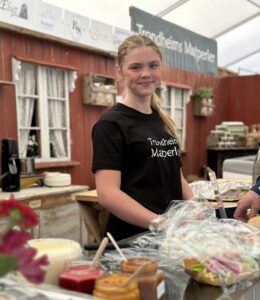 Matperle -jente - på matfestival bak disk med lokale matvarer